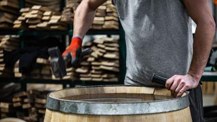 Cooper adjusting an oak barrel with a mallet at Tonnellerie Remond.