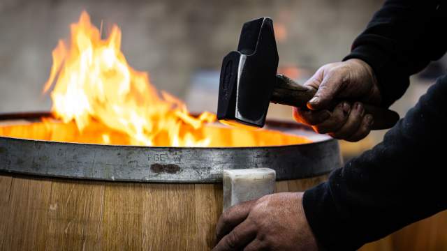 Tonnelier ajustant un fût en chêne chauffé à la flamme à la Tonnellerie Remond.