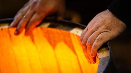 Mains d’un tonnelier contrôlant la chauffe d’un fût en chêne Remond.